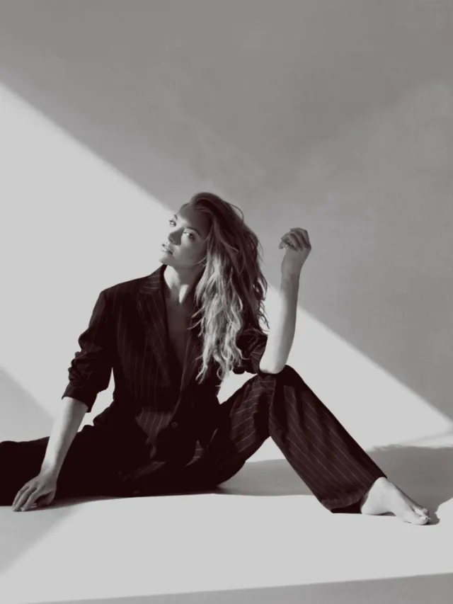Natalie Dormer sitting on a studio floor in a monochrome portrait.