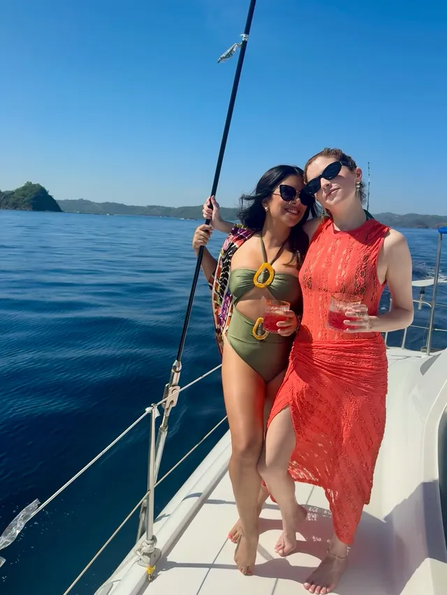 Anna Kendrick standing barefoot beside a friend on a boat deck.