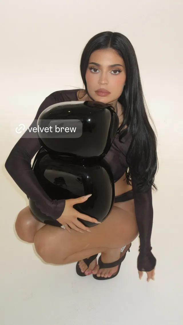 Kylie Jenner posing in a black outfit holding a black bag.