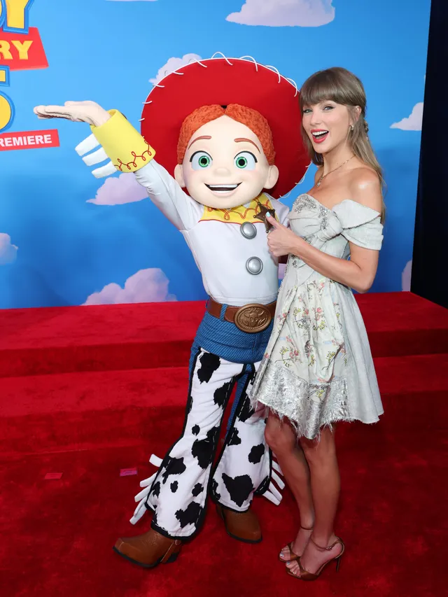 Taylor Swift posing beside a costumed character at a premiere.
