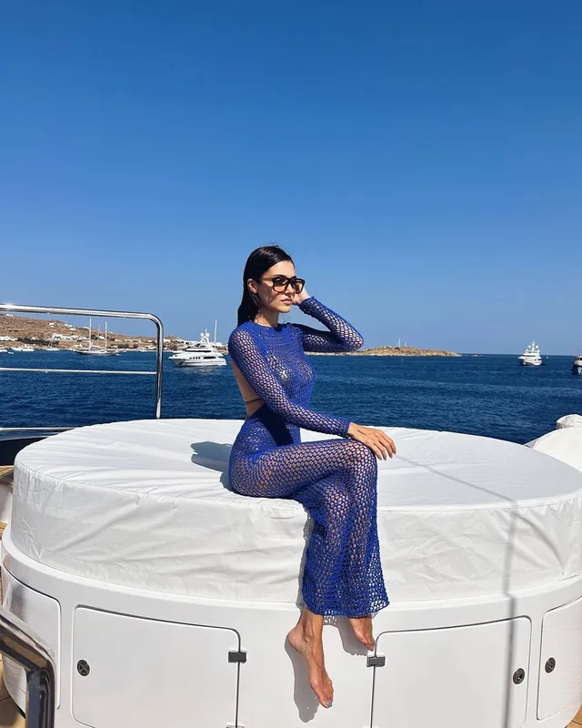 Hande Erçel sitting barefoot on a boat.