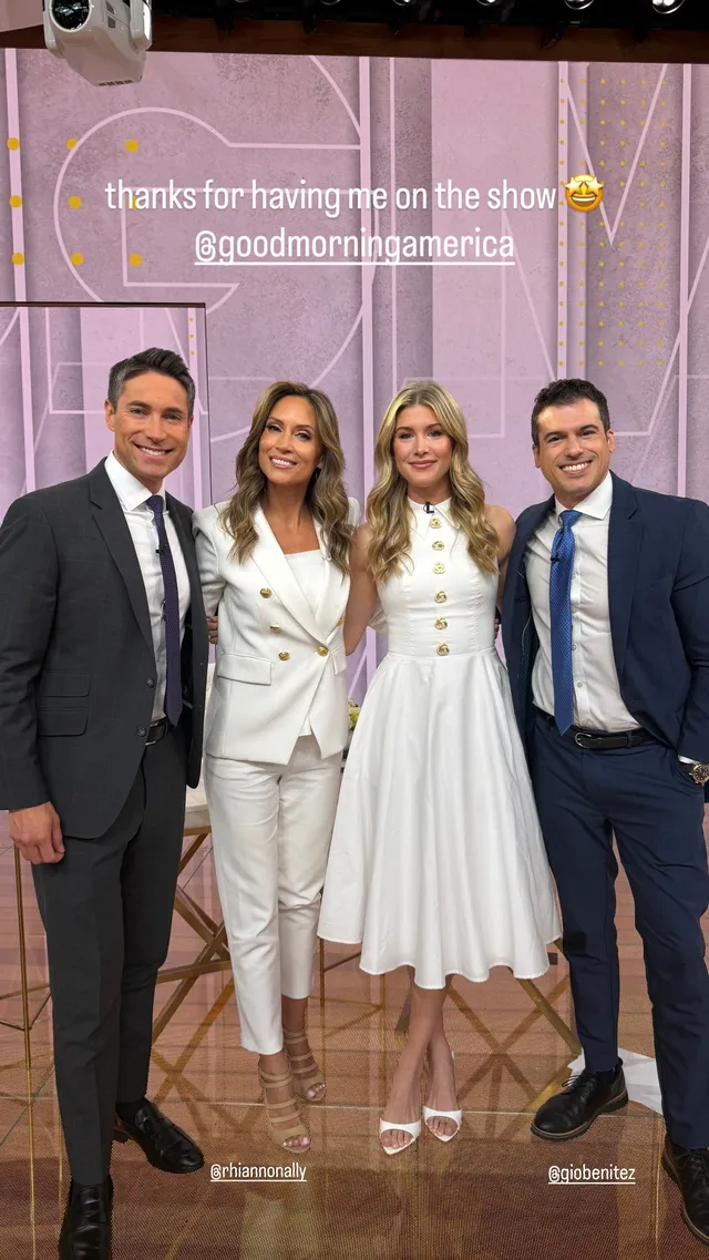Eugenie Bouchard posing beside television presenters in pale heeled sandals and a white dress.