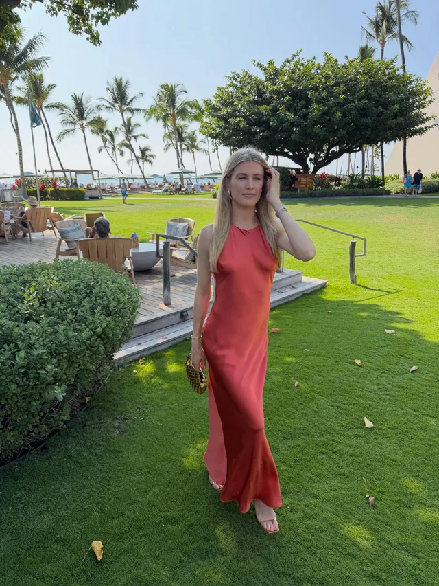 Eugenie Bouchard standing in pale heels and a red dress beside a garden path.