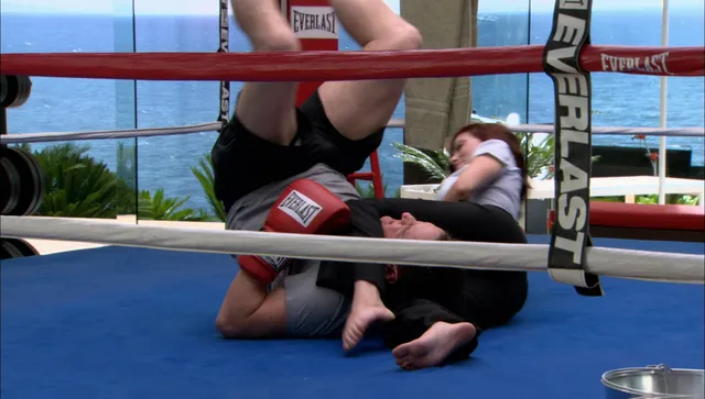Scarlett Johansson sitting in a boxing ring beside a companion.