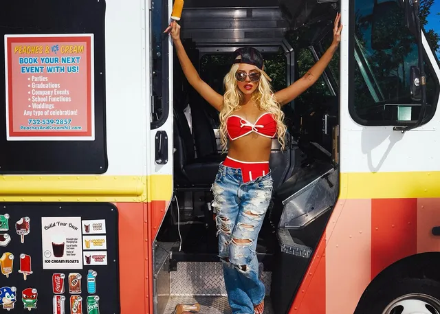 Christina Aguilera posing in an ice-cream van doorway in jeans and heels.