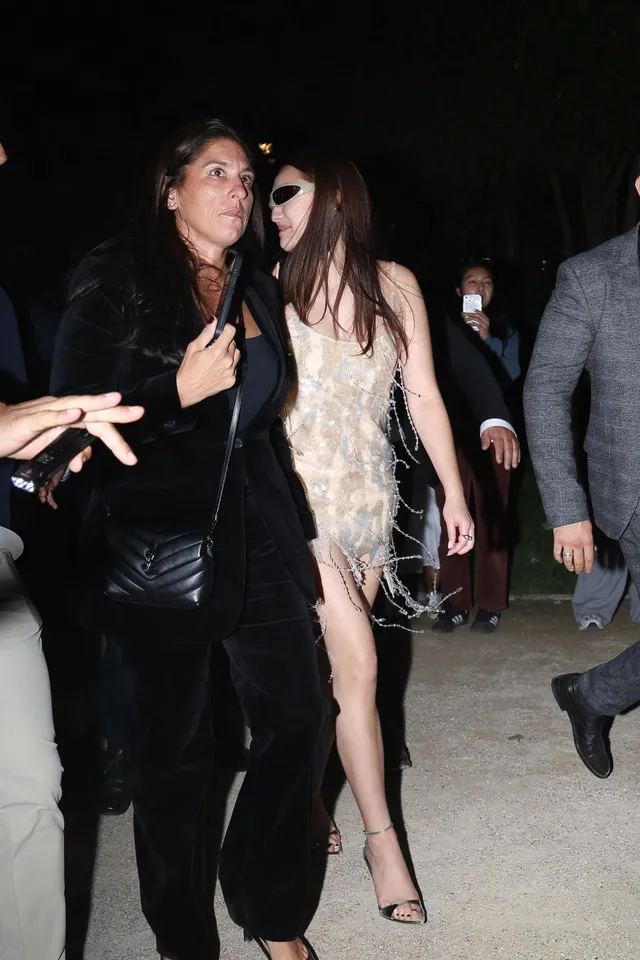 Lola Tung walking with guests in a pale feathered dress and heels.