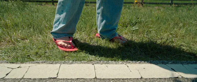 Mckenna Grace wearing flat sandals beneath jeans outdoors.