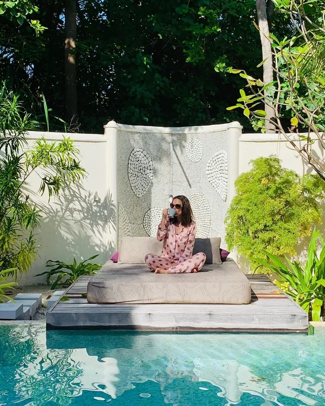Hayley Atwell sitting on a daybed beside a pool.
