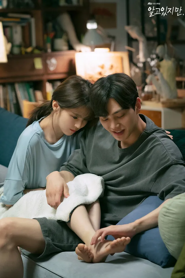 Han So-hee sitting barefoot on a sofa with a book.