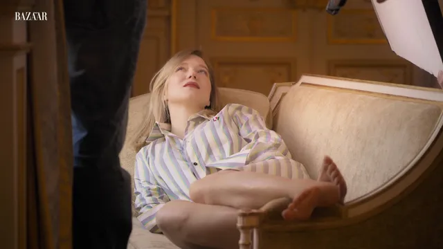 Léa Seydoux reclining on an ornate sofa during a fashion shoot.