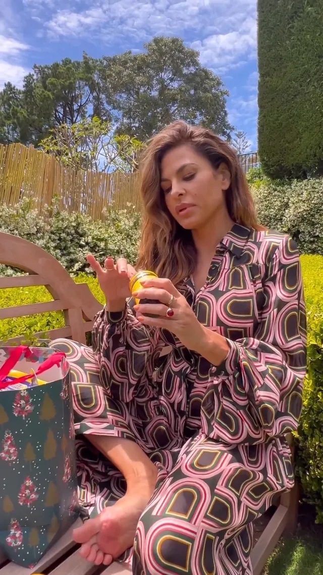 Eva Mendes sitting outside in a patterned dress.