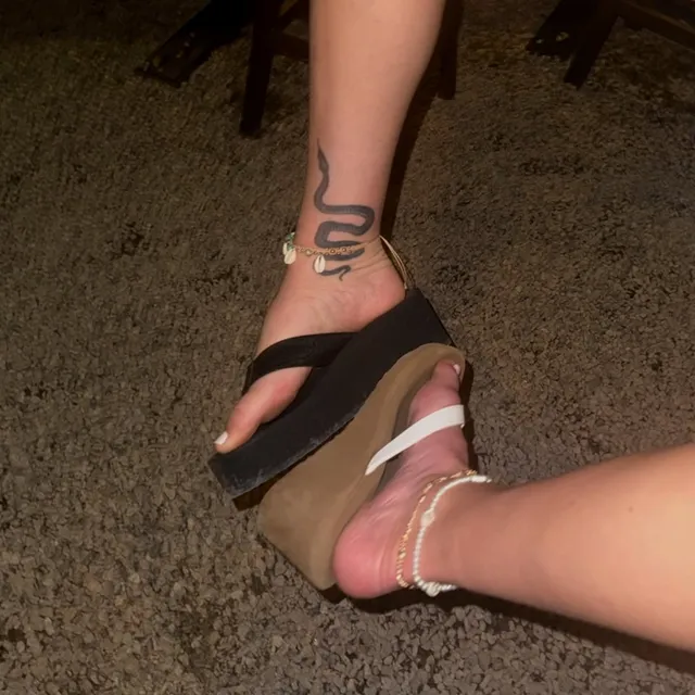 Maika Monroe wearing platform flip-flops beside a companion.
