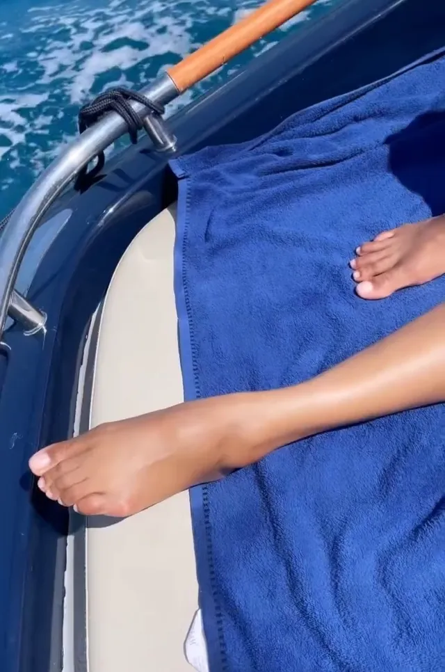 Zoe Saldaña resting bare feet on a boat beside a blue towel.