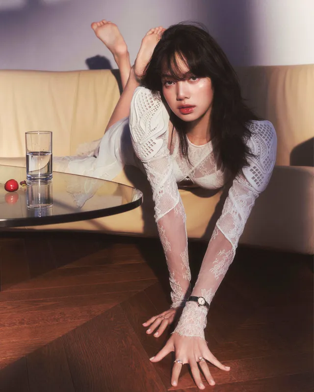 Lisa (Lalisa Manobal) balancing barefoot in a white top and dark skirt during an indoor fashion shoot.