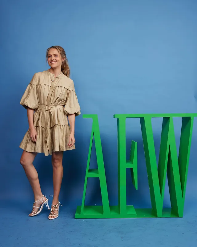 Teresa Palmer posing at a fashion event in a tan outfit.