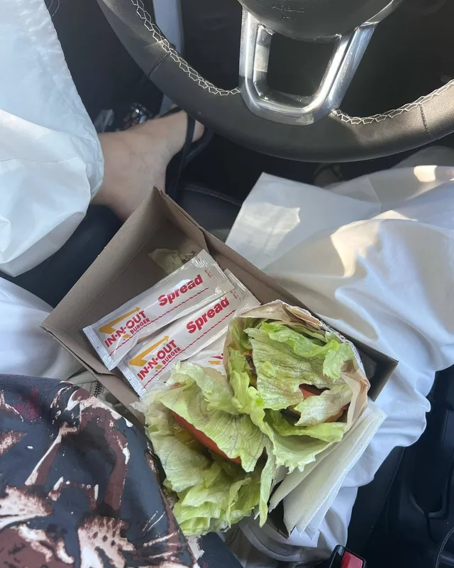 Maia Mitchell sitting in a vehicle wearing black flat sandals.