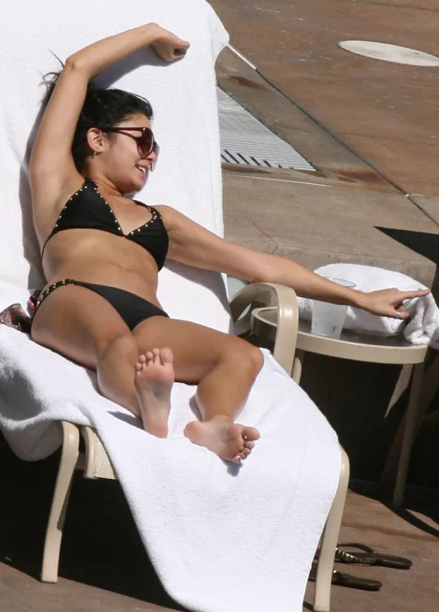 Vanessa Hudgens sitting in a beach chair with bare soles visible.