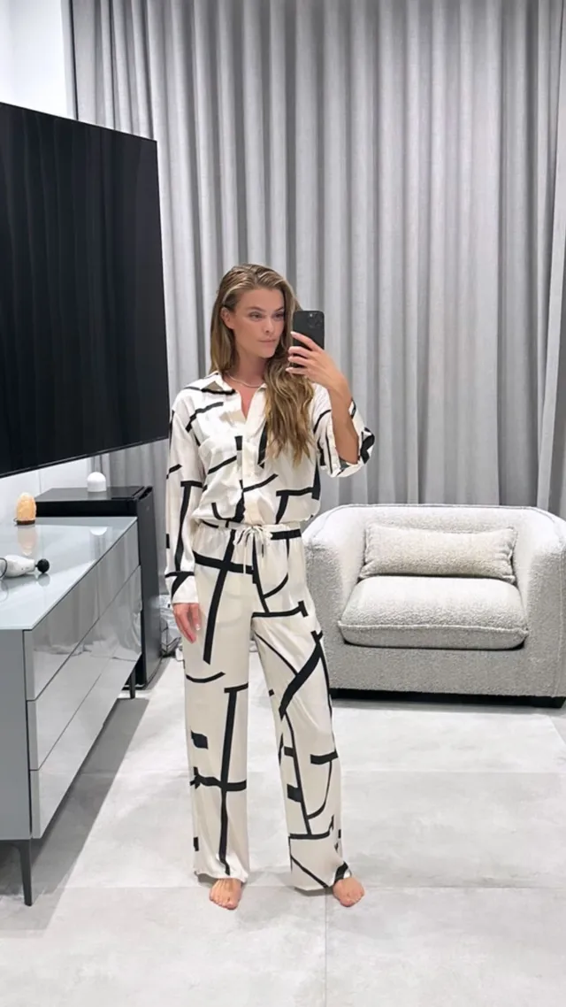 Nina Agdal taking a barefoot mirror photograph in patterned sleepwear.