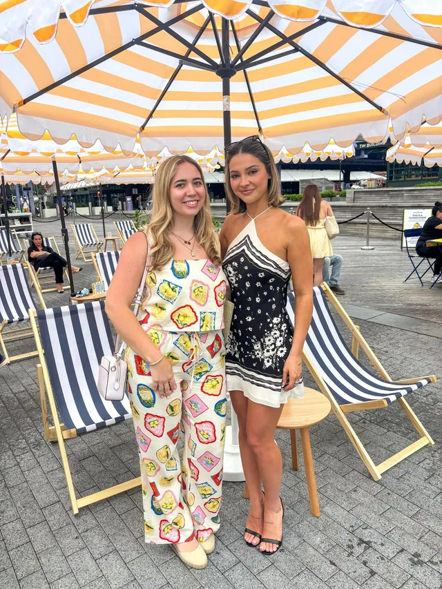 Madelyn Cline posing with another woman outdoors in black heeled sandals.