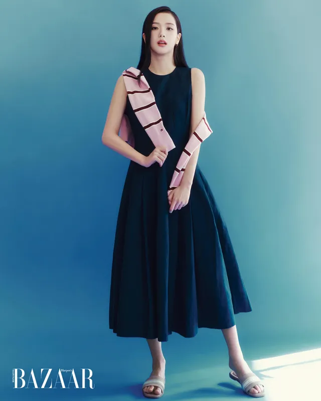 Jisoo standing in pale flat sandals and a dark dress during a magazine shoot.