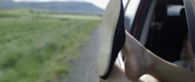 Maika Monroe resting a bare foot outside a vehicle window.