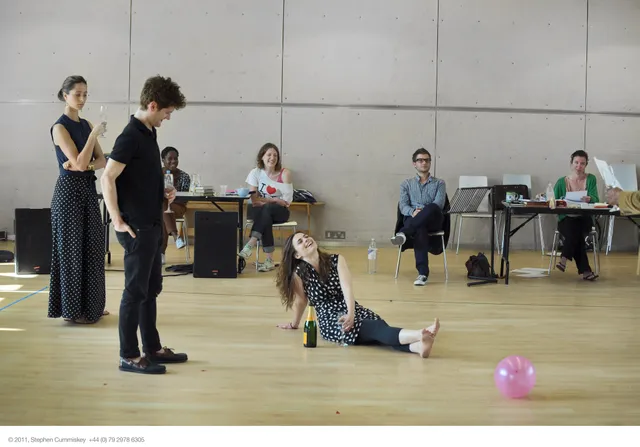 Hayley Atwell sitting on a rehearsal room floor among performers.