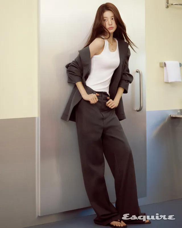 Jang Wonyoung standing indoors in a suit and flat shoes.