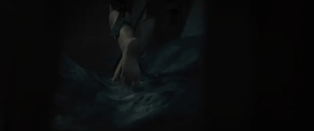 Cailee Spaeny placing a bare foot on a metal surface in a film scene.