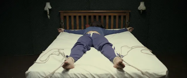 Gemma Arterton lying across a bed in a dramatic scene.