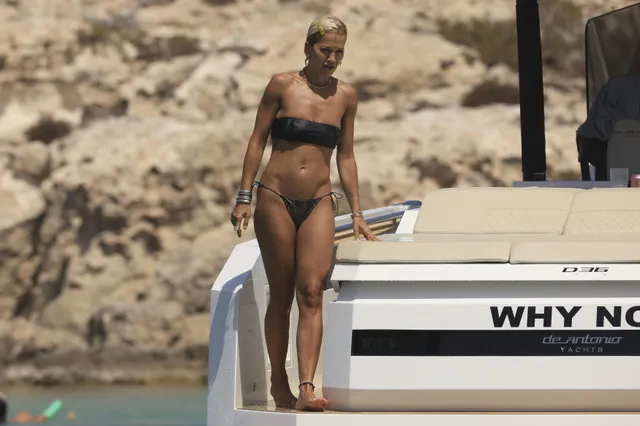 Rita Ora walking barefoot beside a boat.