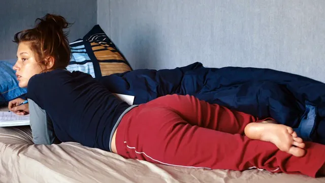 Adèle Exarchopoulos reclining on a sofa in red trousers.