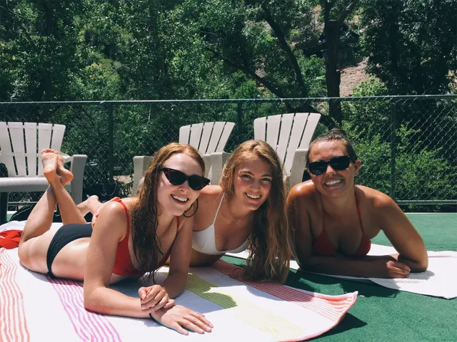 AnnaSophia Robb posing with companions beside a swimming pool.