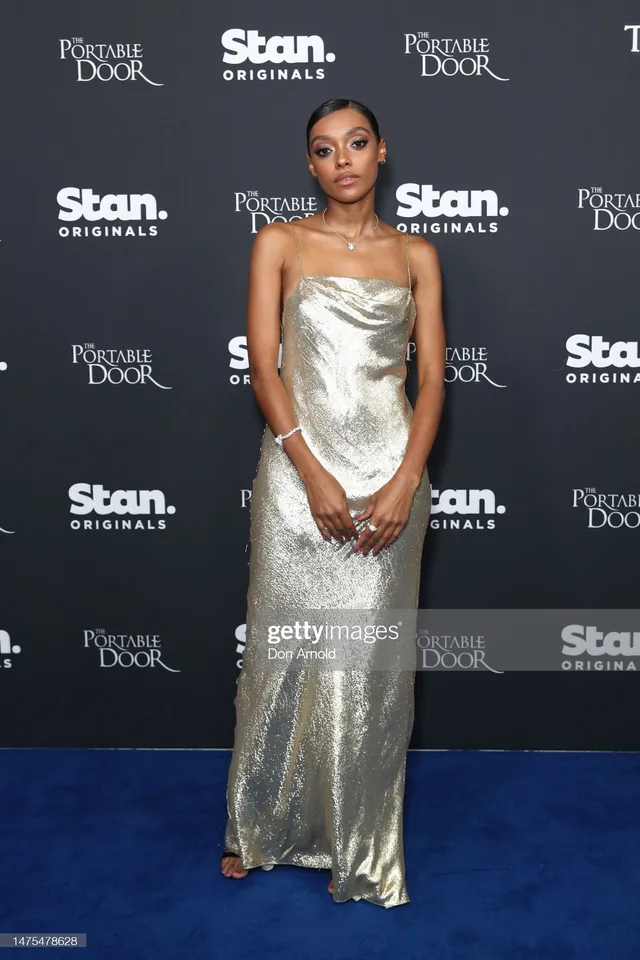 Sophie Wilde wearing a floor-length silver dress on a blue carpet.
