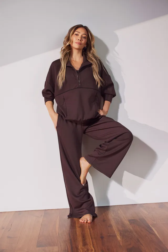 Hilary Duff posing barefoot in a loose dark suit.