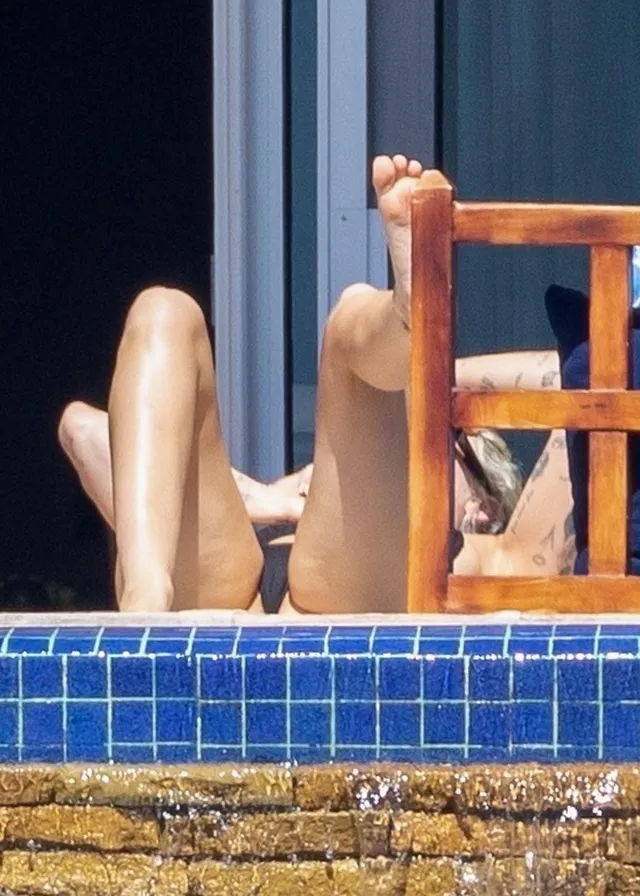 Miley Cyrus raising a bare sole beside a tiled pool.