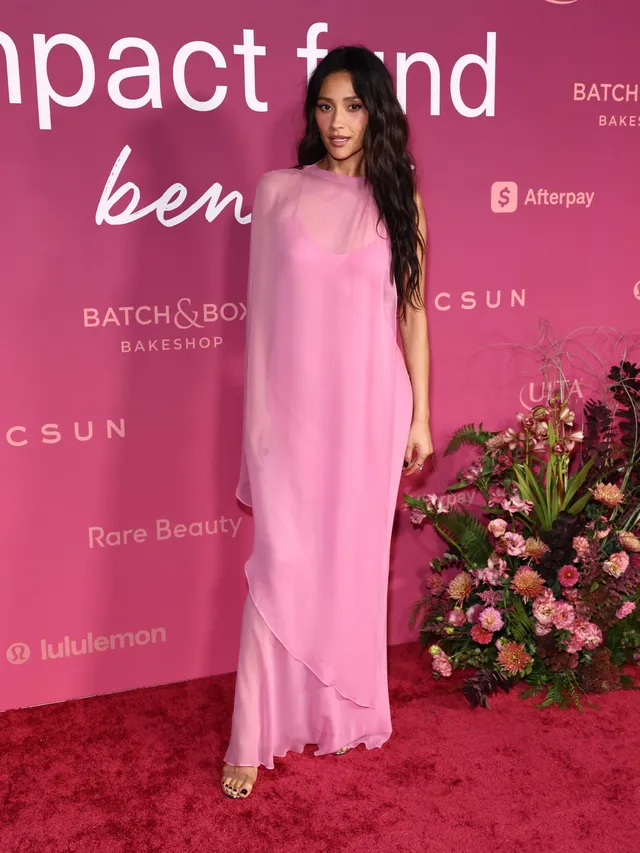 Shay Mitchell posing on a pink carpet in a long pink dress.