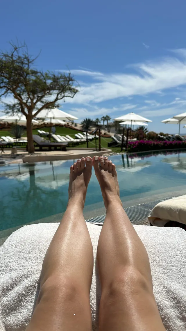 Ashley Tisdale resting her bare feet beside a poolside lounger.