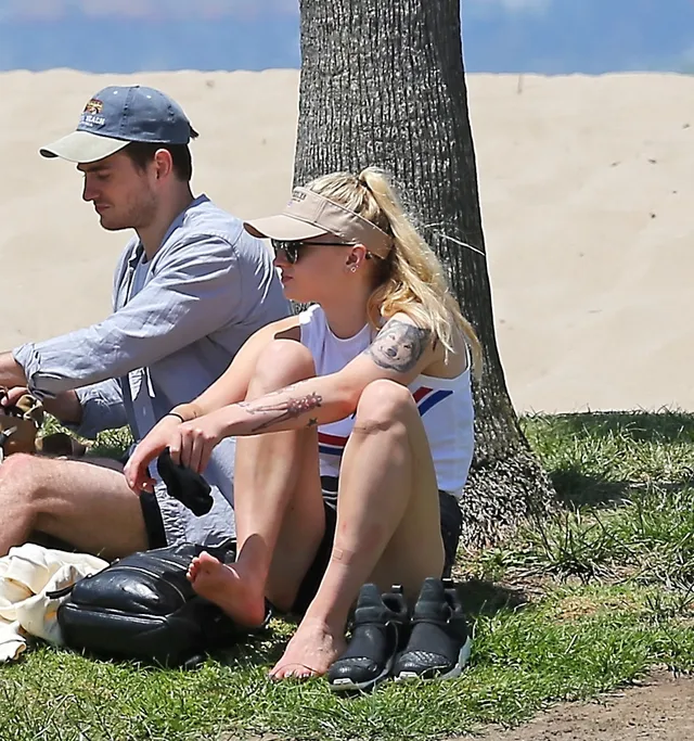 Sophie Turner a casual seated photograph on grass.
