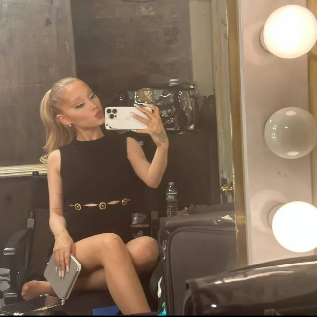 Ariana Grande taking a seated mirror selfie.