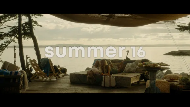 Emily Alyn Lind standing barefoot on a terrace beside the sea.