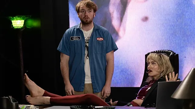 Olivia Wilde sitting with her bare feet resting on a desk during an interview.