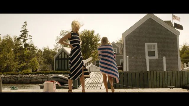 Emily Alyn Lind standing barefoot on a boat in a striped towel in a scene.