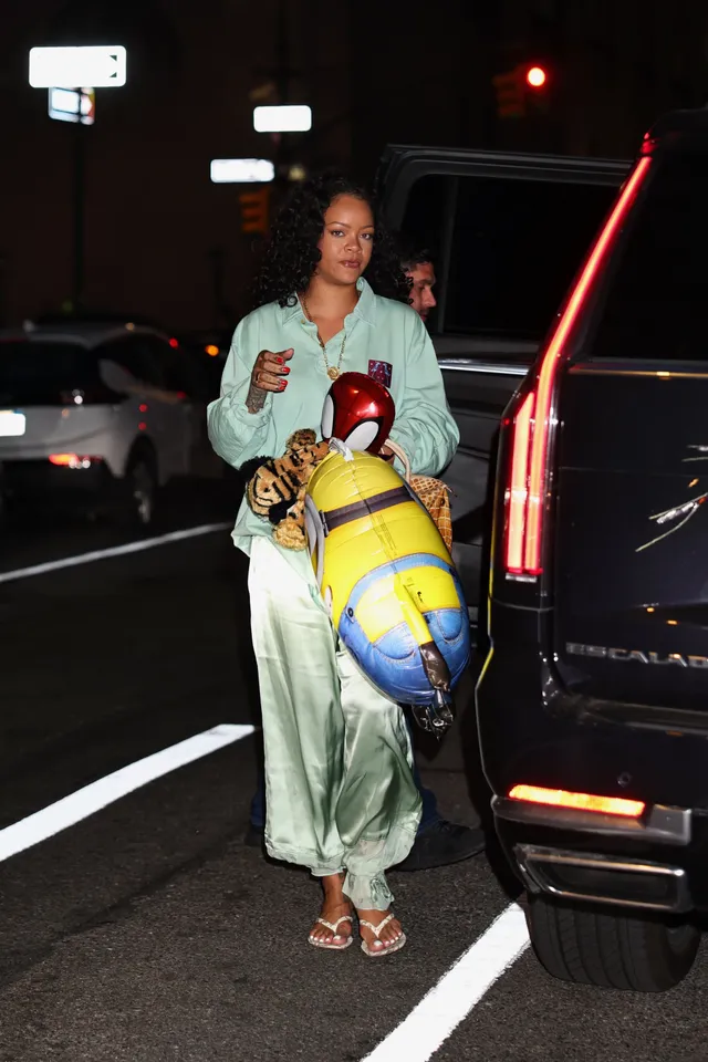 Rihanna stepping out of a car in a pale green outfit and flat sandals.