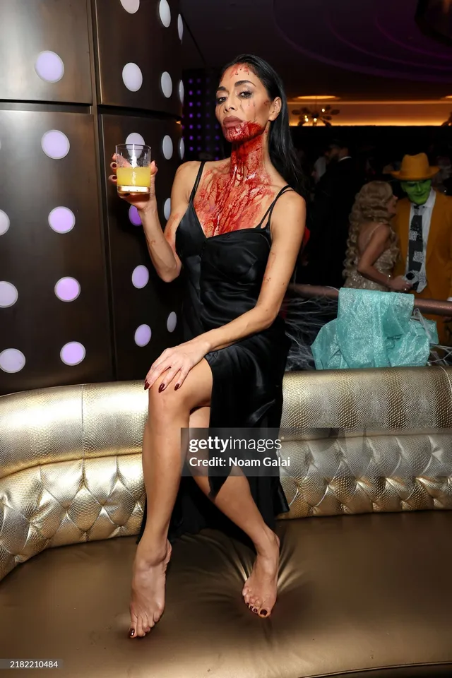 Nicole Scherzinger sitting barefoot in a dark dress at a birthday celebration.
