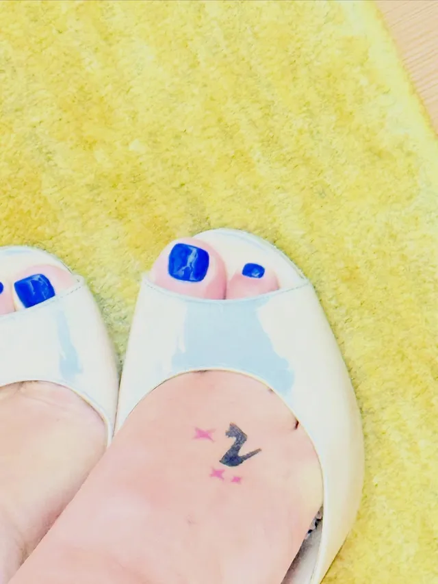 Addison Rae a close view of blue-painted toenails in white open-toe sandals.