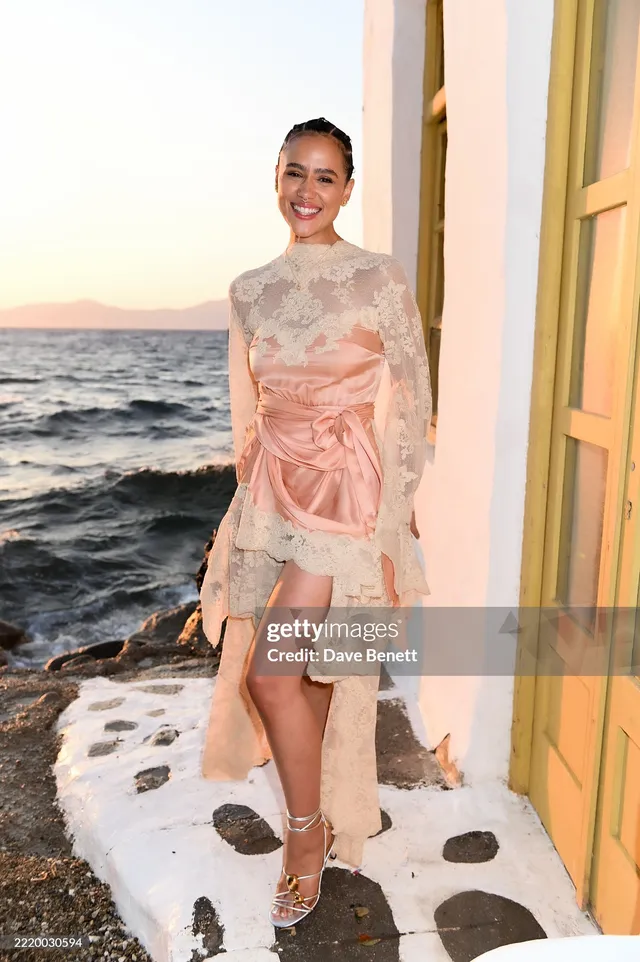 Nathalie Emmanuel standing beside a yellow door in an embellished outfit.