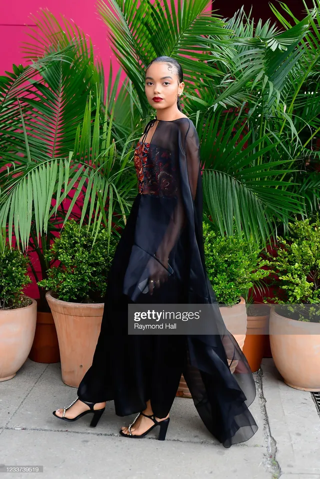 Whitney Peak wearing an embellished top, long black skirt and heels outdoors.