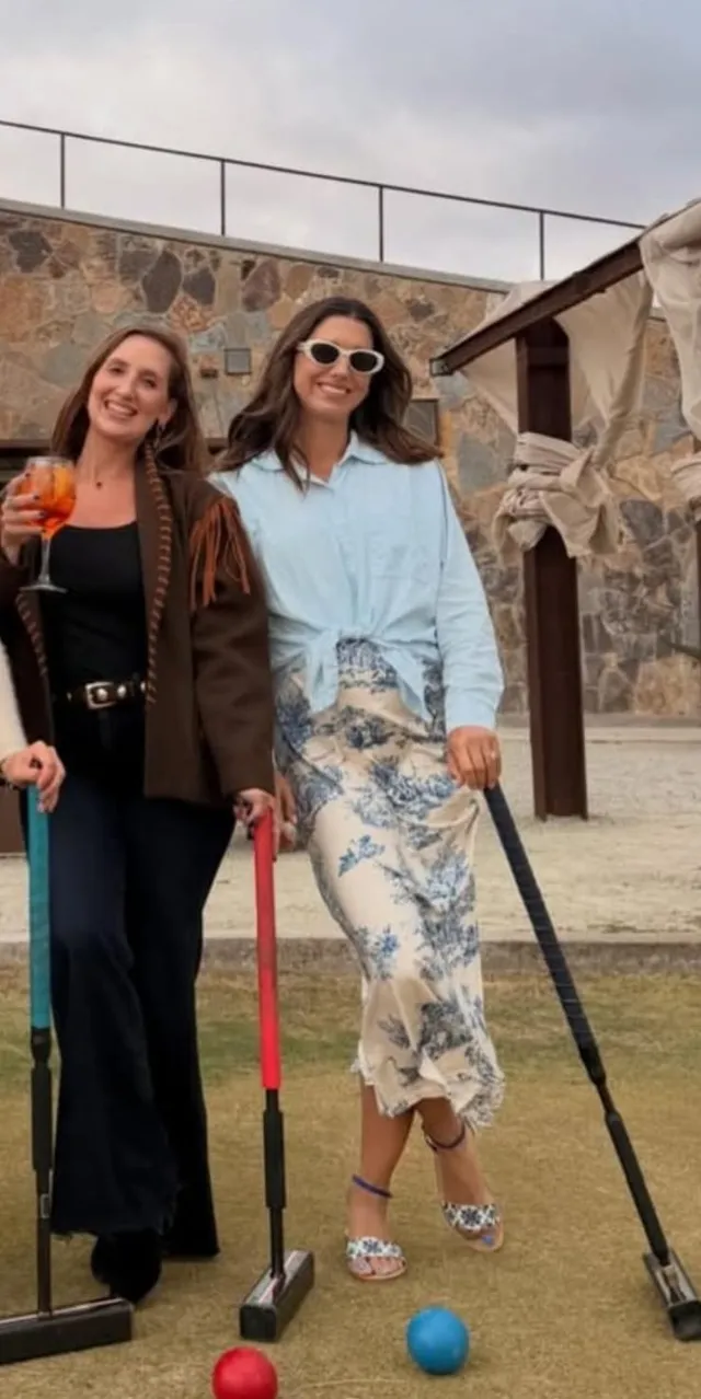 Alex Morgan posing with a companion outdoors in flat sandals and a pale dress.