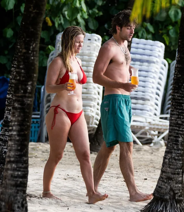 Alice Eve walking with a companion on a beach.