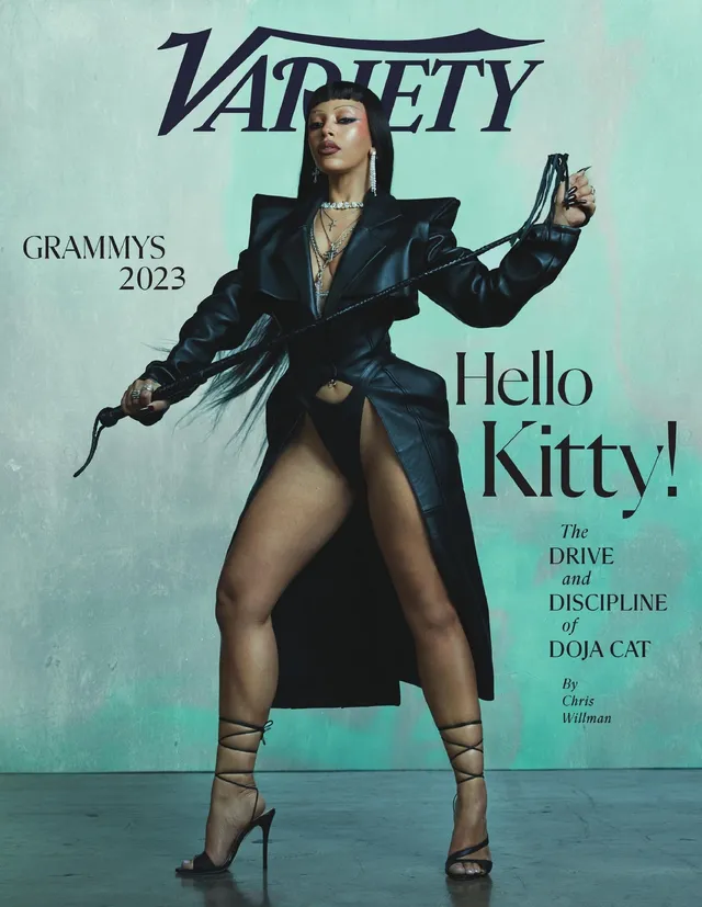 Doja Cat posing in a black outfit and lace-up heels in a magazine photograph.
